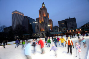 The city lights of Providence serve as a backdrop for ice skaters at the Alex and Ani Skating Rink