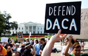 Protestor holding sign reading "defend DACA"