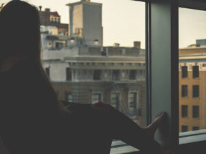 A woman looking woefully out a window