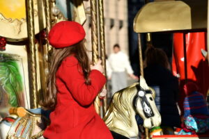 Little girl holding onto a horse on a carousel