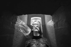 A woman blindfolded by her hair trapped in a jail cell