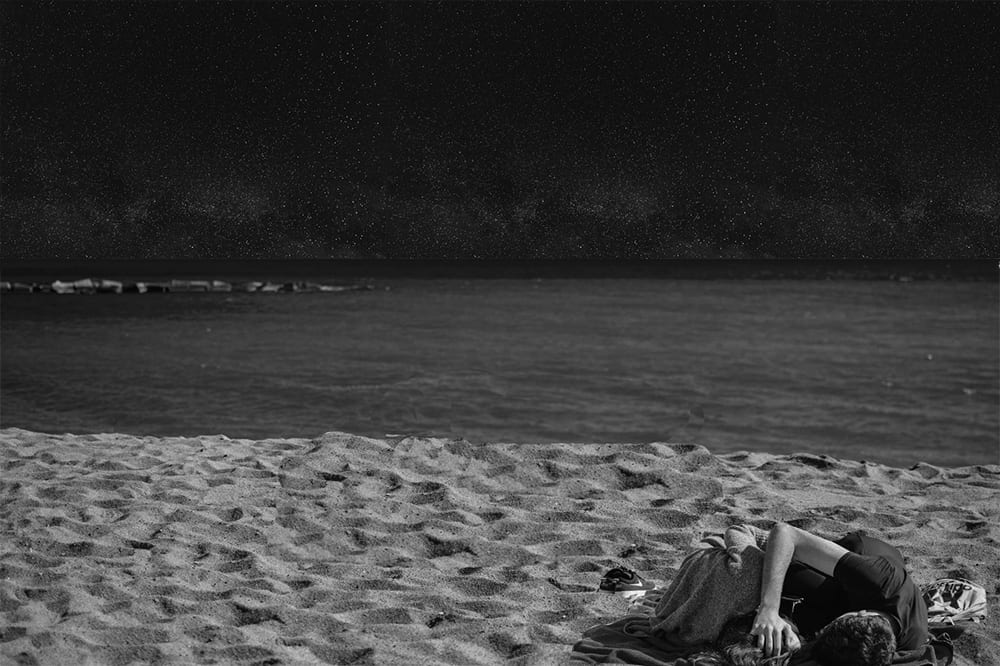 Man and woman lying on the beach under the night sky