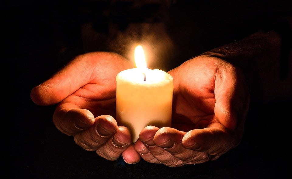 Hands holding a little candle that is lit