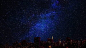 A starry night with a well lit skyline