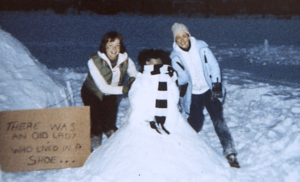 Two woman build a snowman during a storm on Providence College's campus