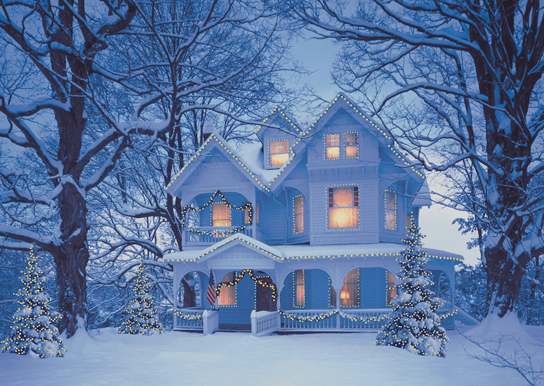 house in the snow lit up by Christmas lights