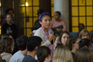 a student asking a question in a crowd using a microphone