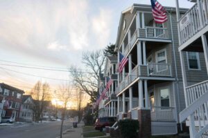 photo of the sun setting behind houses flying American flags