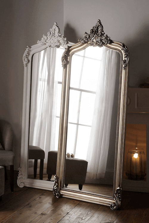 two full-length mirrors leaning against a wall with a fireplace