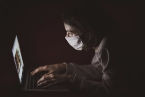 person wearing a mask looking at a computer