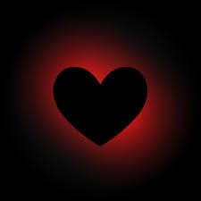 A black heart with a hue of red in a dark background