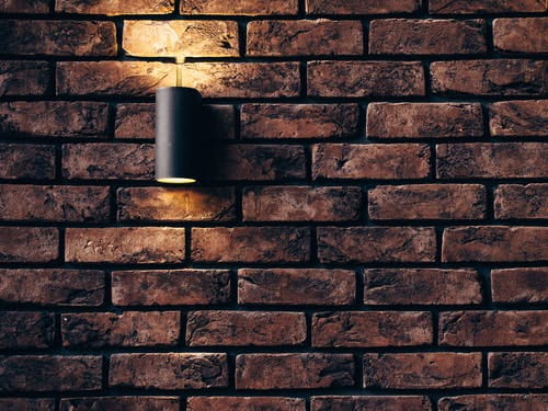 a brick wall with a small lamp attached