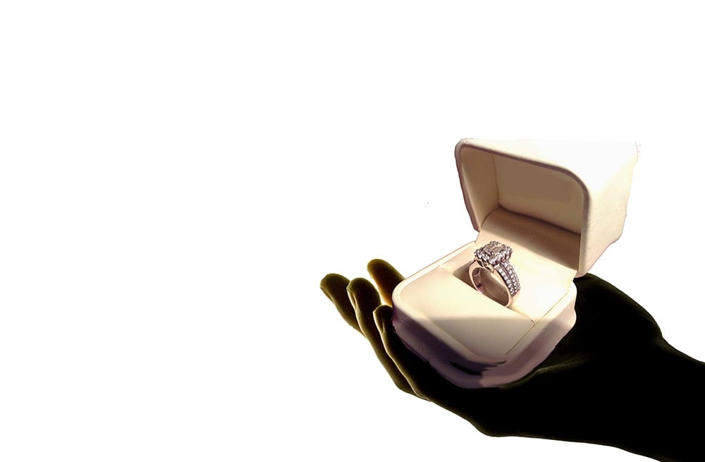 Man proposing to his wife with an engagement ring in a velvet box 