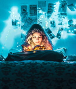 Woman reading a book in her bedroom under the blue tinge of string lights surrounding the room 