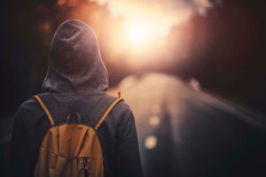 Traveler with backpack walking forward alone at sunset