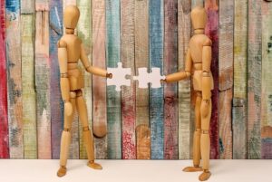 two wooden models putting puzzle pieces together 