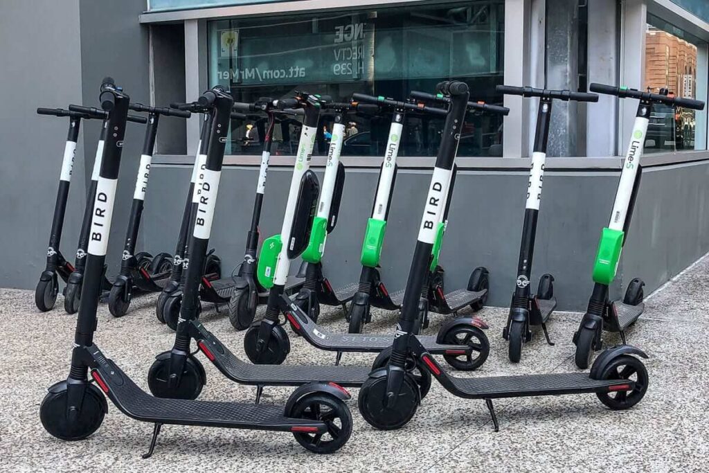 Line of electric scooters on a sidewalk.
