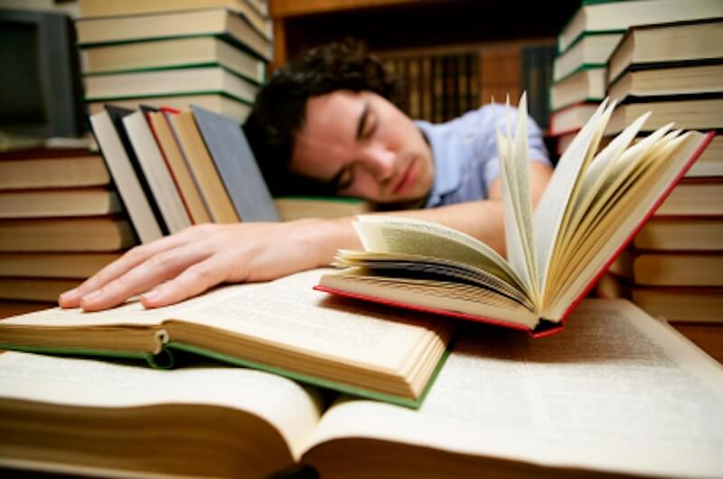 Student falling asleep while studying in the library.