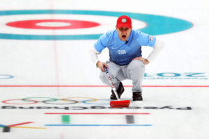 John Shuster of the USA curling team finishes a sweep during the gold medal round.